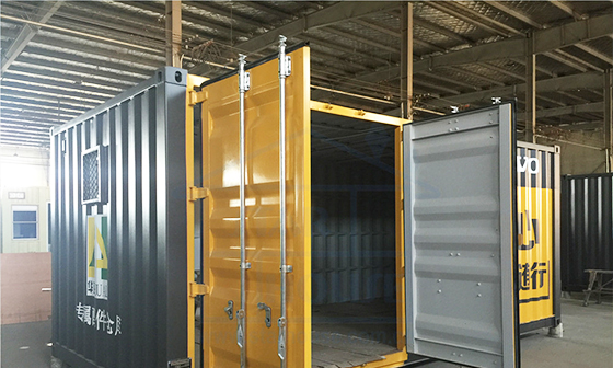 A dark modified container with framed door and window openings during production